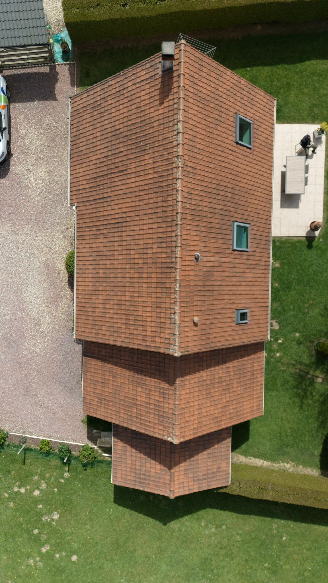 Vue aerienne d'un toit en tuiles rouges avec terrasse et jardin autour
