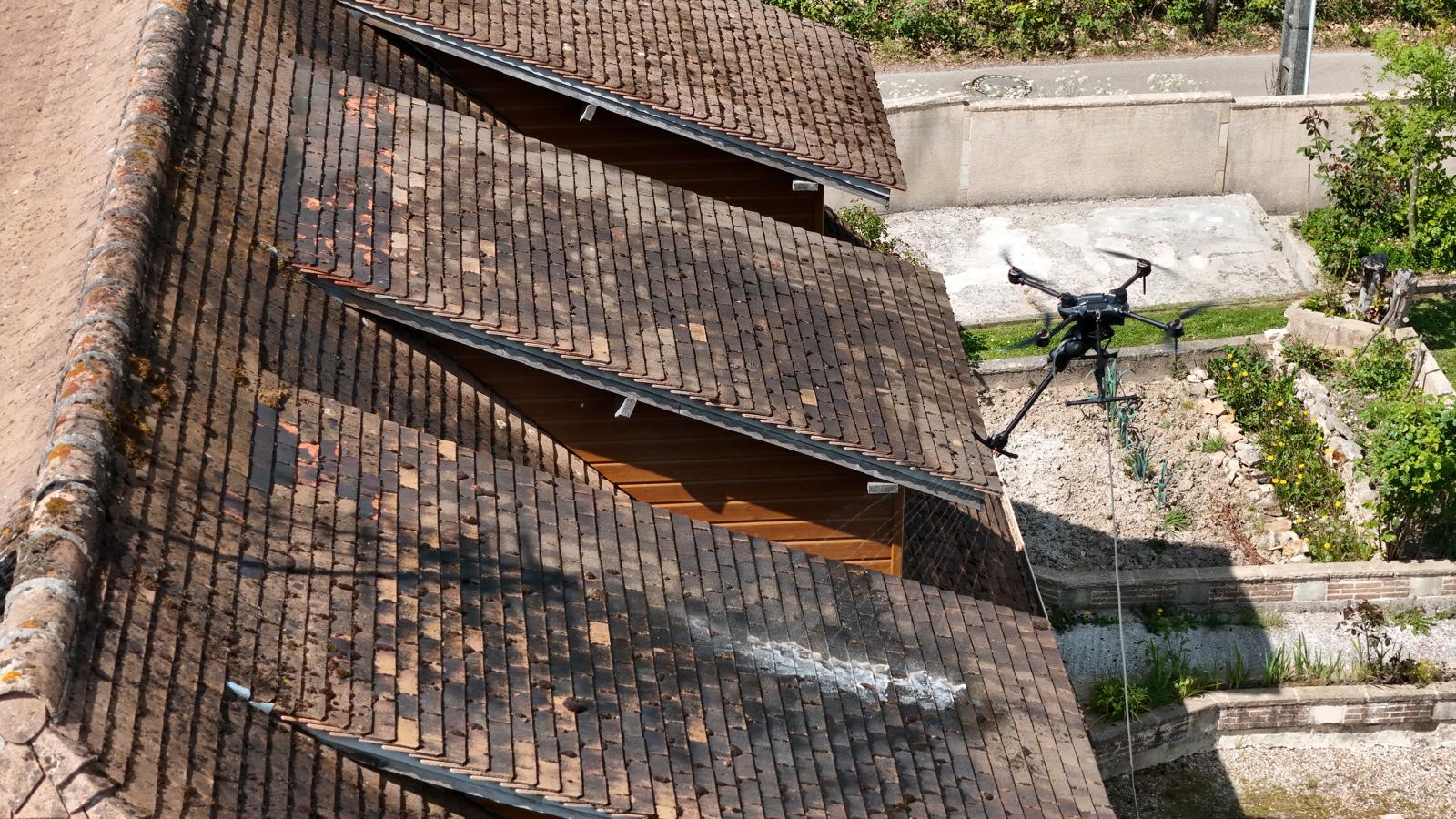 Drone effectue nettoyage de toiture en tuiles sur une maison avec jardin