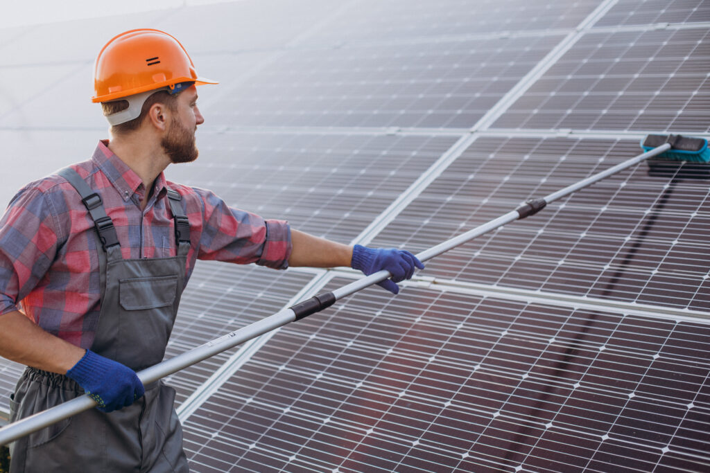 Technicien nettoyant des panneaux photovoltaïques sur un toit