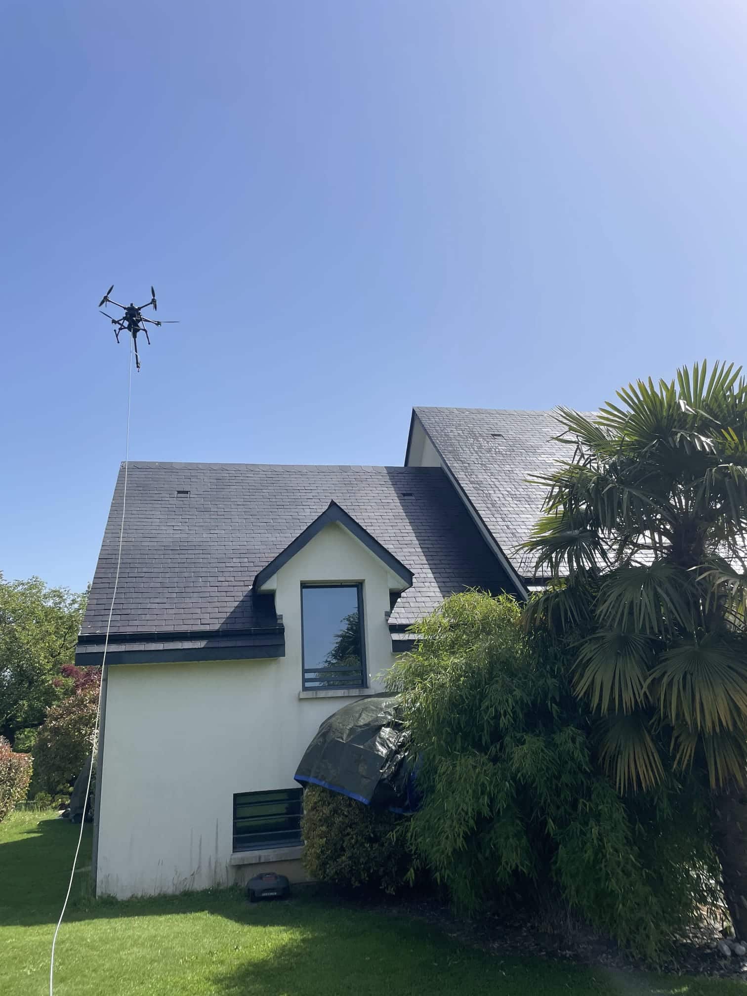 Drone survolant une maison à toiture en ardoise pour un nettoyage sans échafaudage