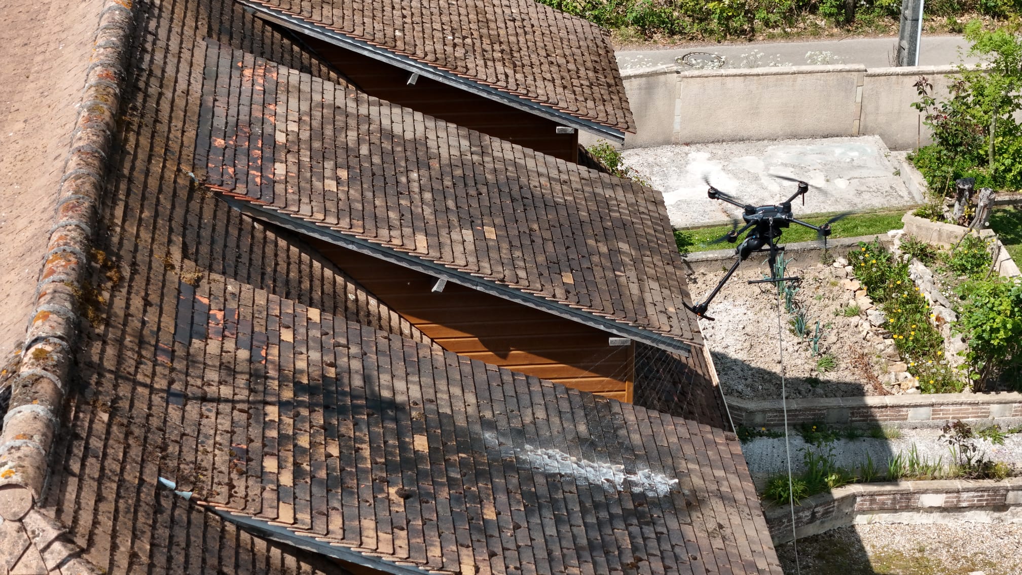 Vue aérienne du drone nettoyant une toiture couverte de mousse en Normandie
