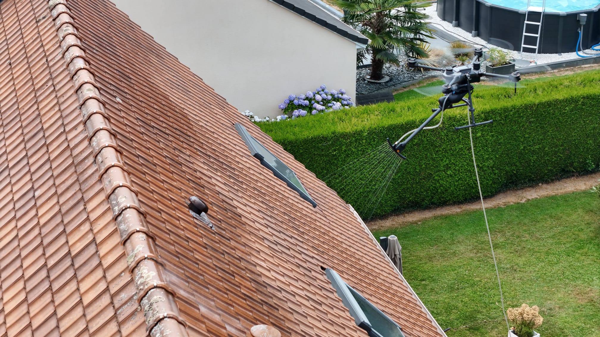 Drone pulvérisant à basse pression sur une toiture en tuiles