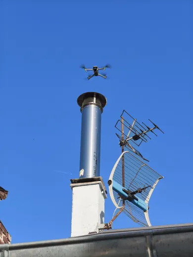 Drone en vol près d'une cheminée et d'une antenne pour une inspection de toiture en Normandie