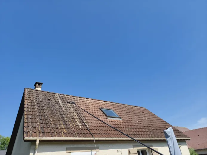 Nettoyage d'une toiture en tuiles à la perche télescopique, bande déjà nettoyée visible